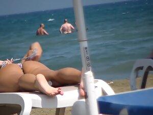 Voyeur inspects fit girl while she sunbathes on beach Picture 6